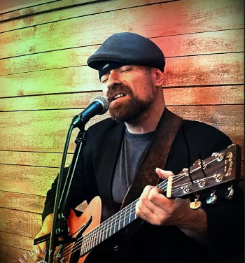 Live music performance at Pindar Vineyards with a singer playing guitar outdoors.