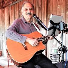 Pindar Vineyards musician playing guitar and singing in a rustic setting.