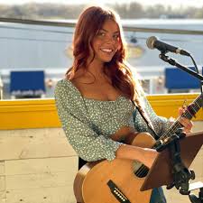Female musician playing guitar at Pindar Vineyards, enjoying live music outdoors.